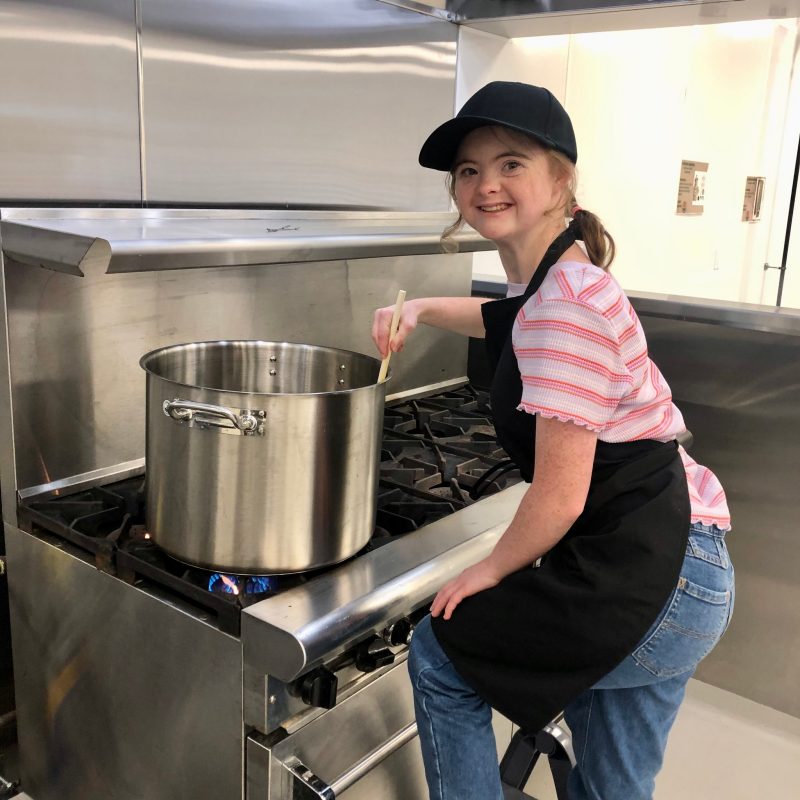 girl cooking in a large pot on the stove